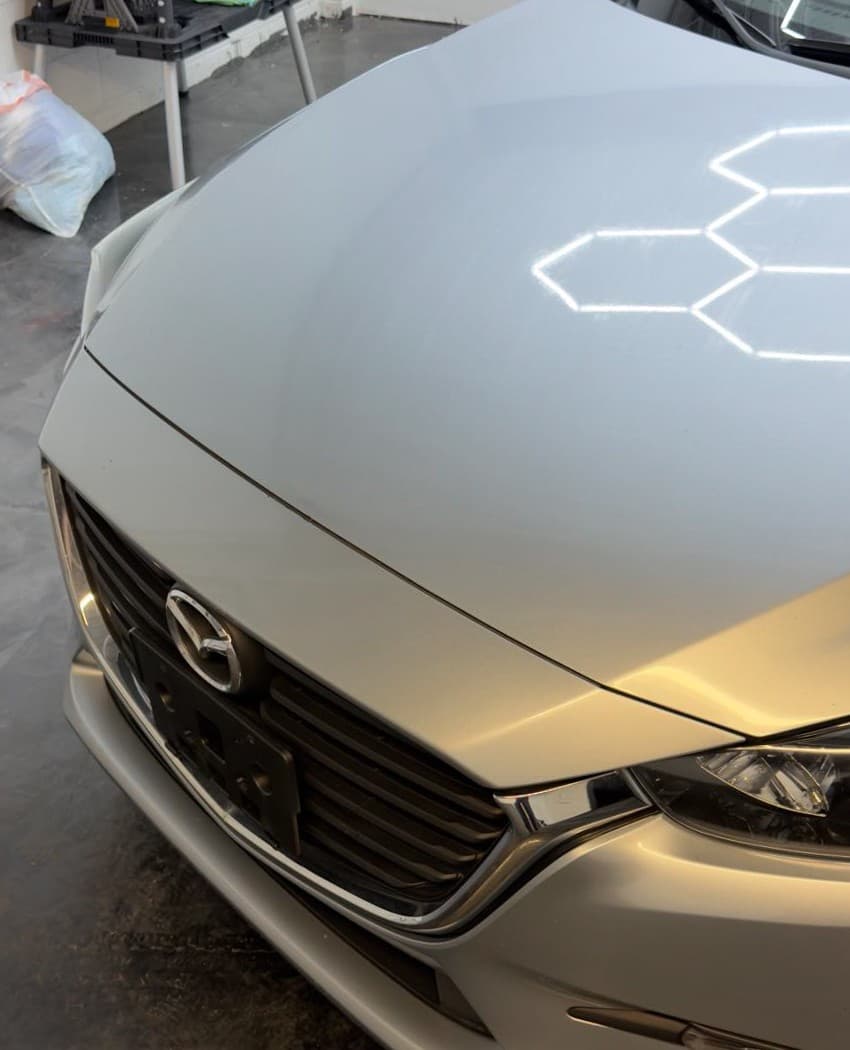 Silver Mazda hood after paint correction — contaminants removed, smooth finish restored