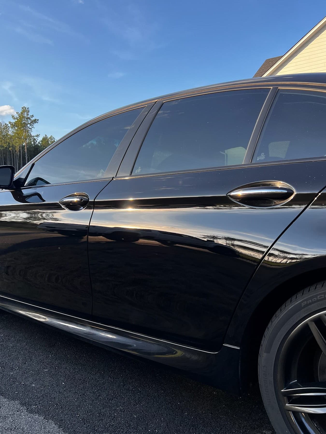 Black BMW side panel after paint correction — scratches removed, deep gloss restored